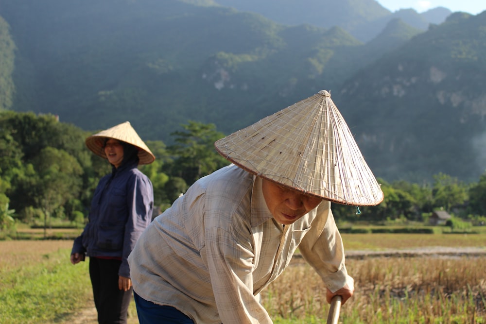 two people wearing straw hats near mountains