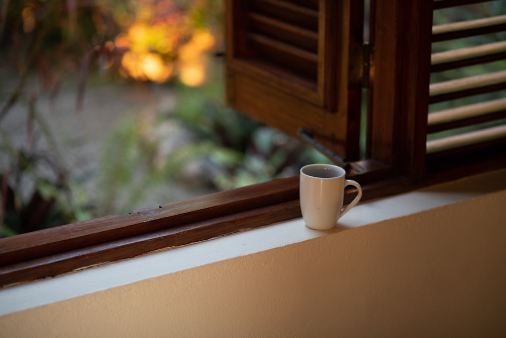 white ceramic mug on white and brown window