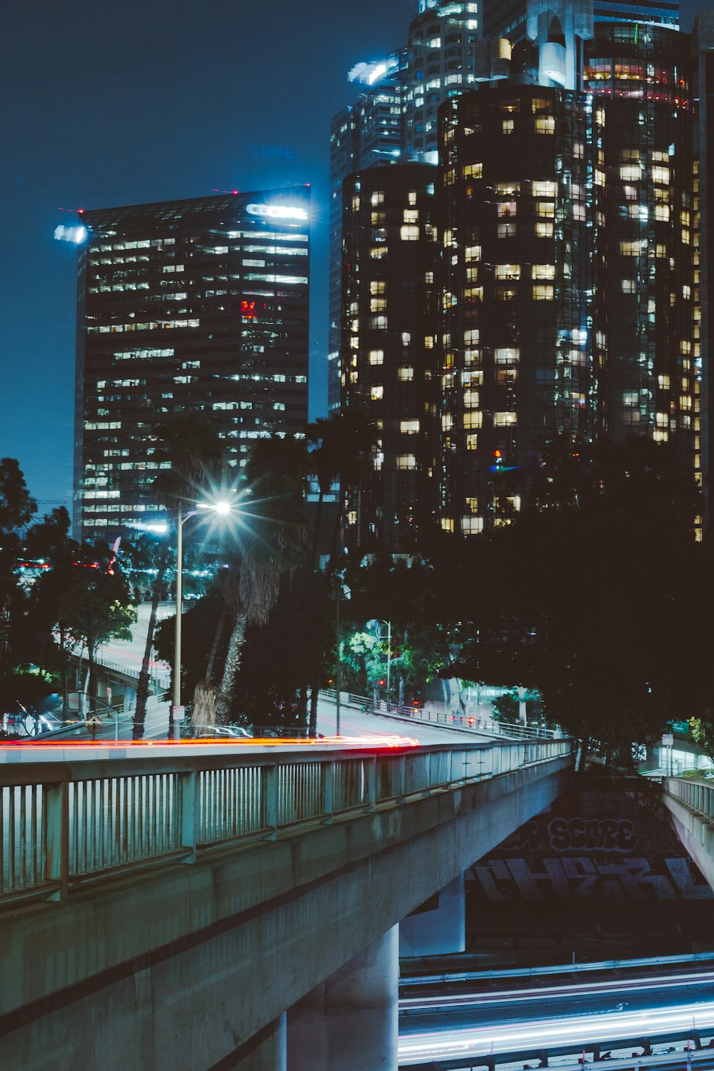 a city skyline at night with a bridge going over it