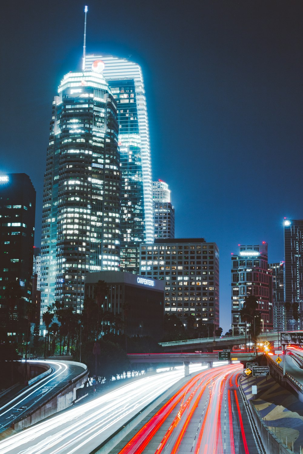 timelapse photography of vehicle passing on roads near buildings at night \