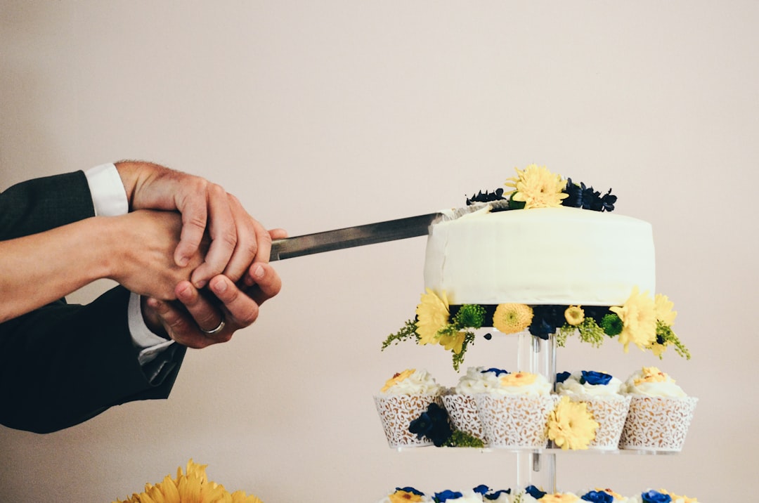couple both holding knife slicing a cake on tray