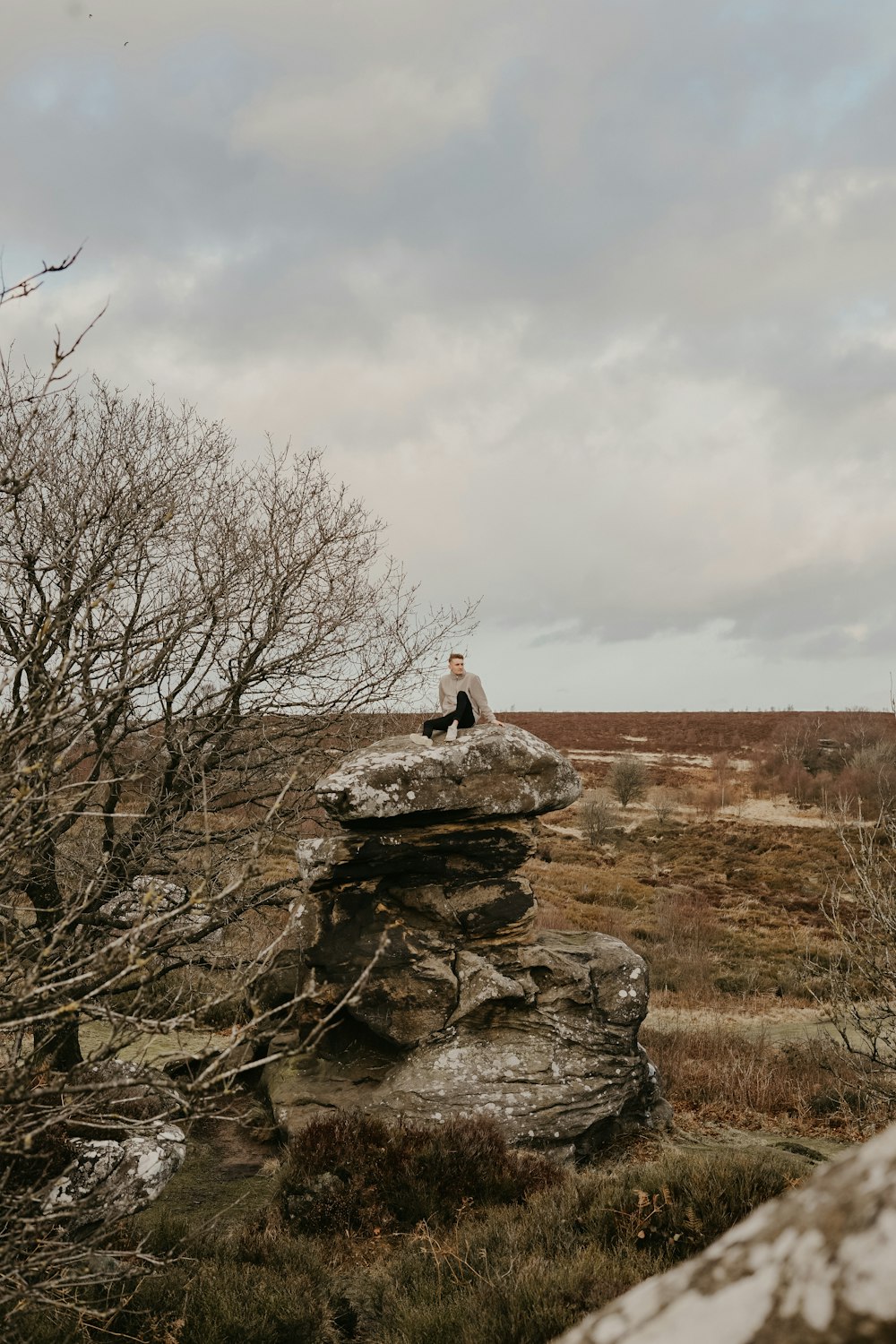 person sitting on piled rocks near trees during daytime