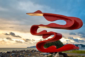 A striking fiberglass sculpture with smooth curves set against a deep maroon backdrop.
