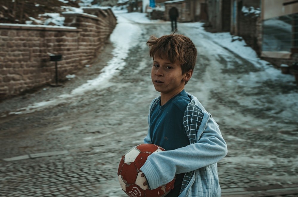 boy holding brown and white ball