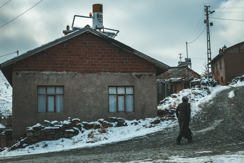 man walking beside gray and brown house during daytime