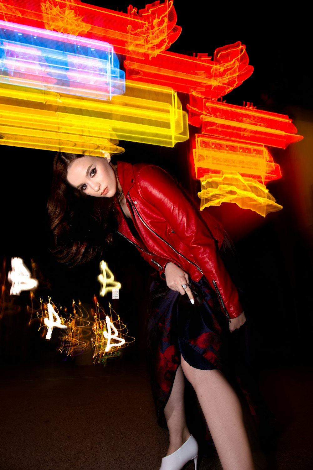 bokeh photography of woman in red leather jacket standing in dark space