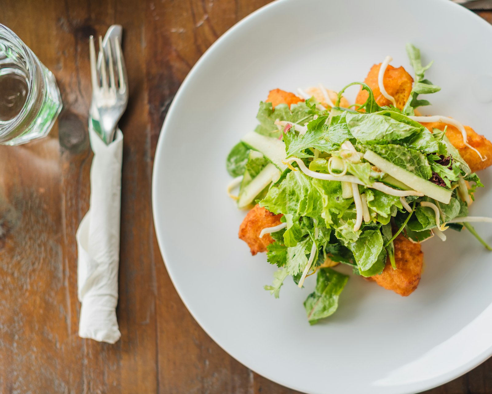 Une assiette de salade verte aux copeaux de fromage, posée près d’une serviette pliée