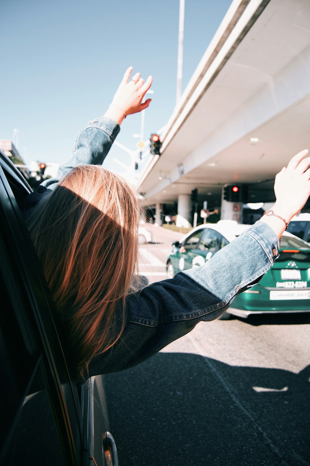 woman waving while riding car during daytime