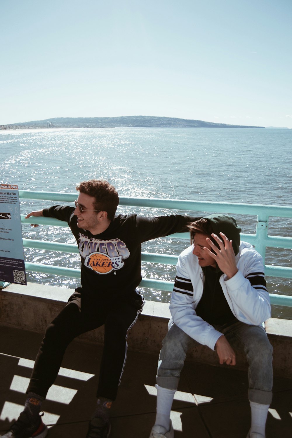 two men sitting on concrete ground near sea