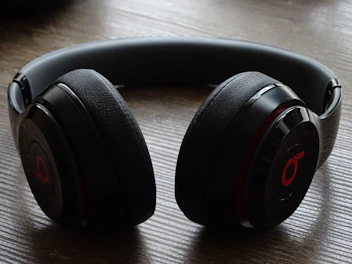 Sleek wireless headphones resting on a black surface with red accents
