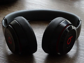 Sleek wireless headphones resting on a black surface with red accents