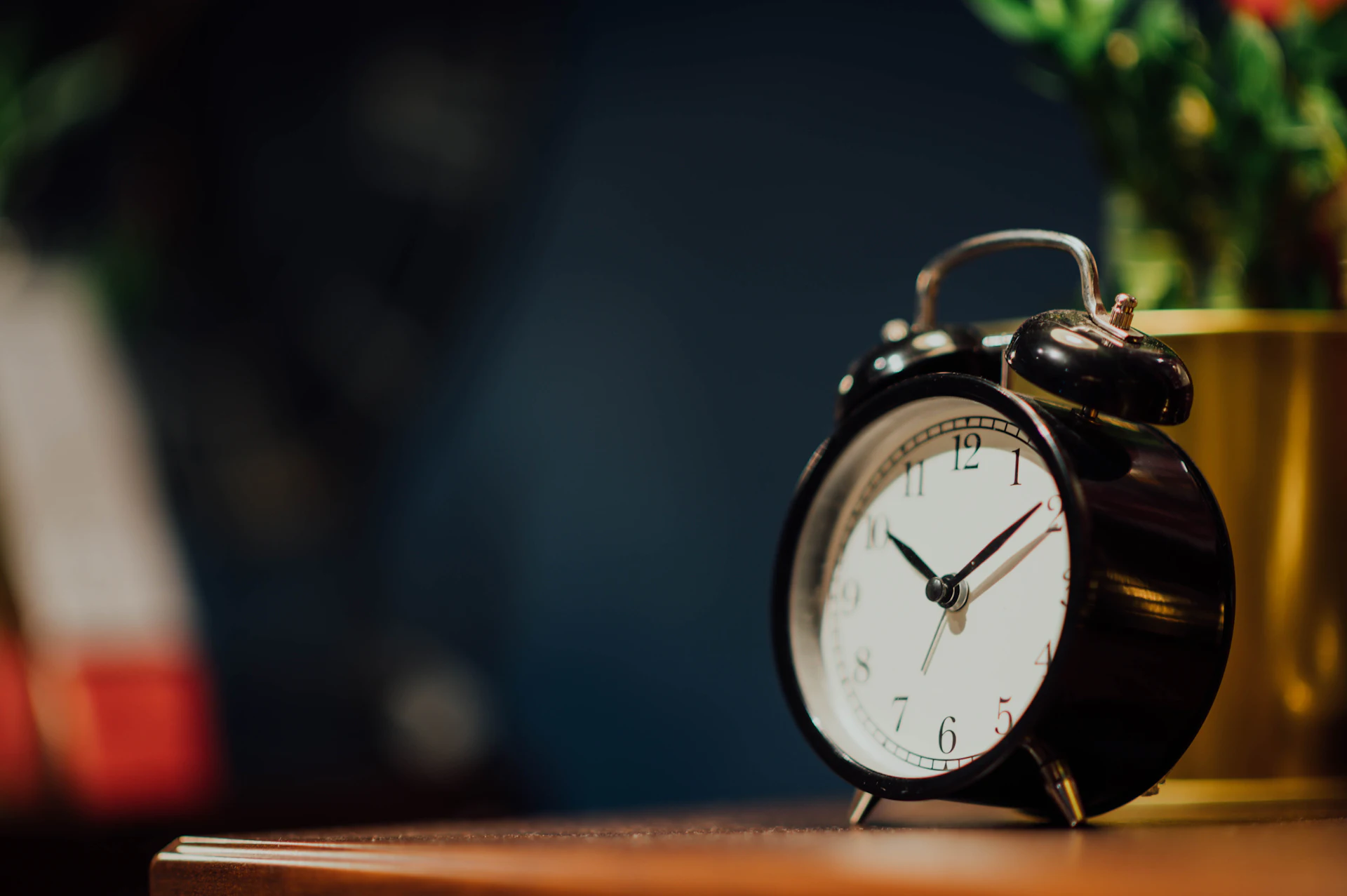 Budzik ze wskazówkami ustawionymi na 10:10 na ciemnym tle