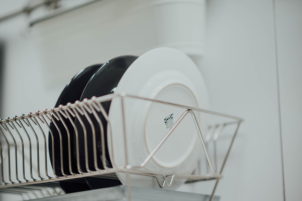 two black ceramic plates and white ceramic plate on stainless steel plate rack