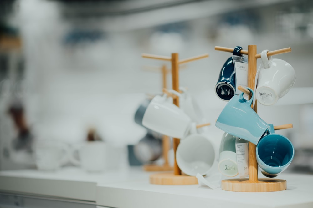 white and blue ceramic mugs on wooden stands on white panel board in selective focus photography