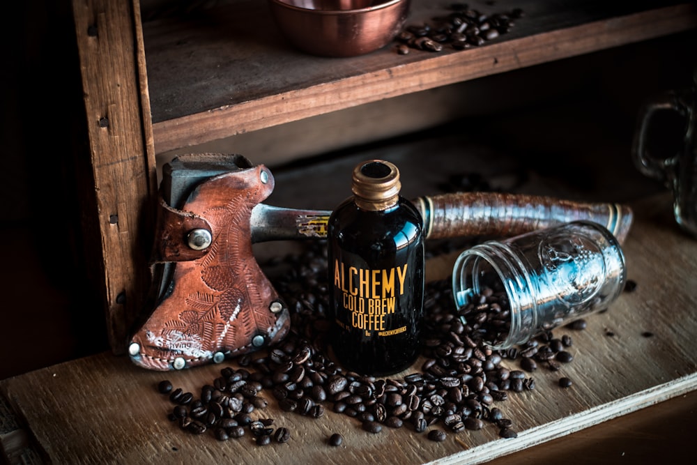 alchemy cold brew coffee bottle near the brown hatchet on brown wooden rack