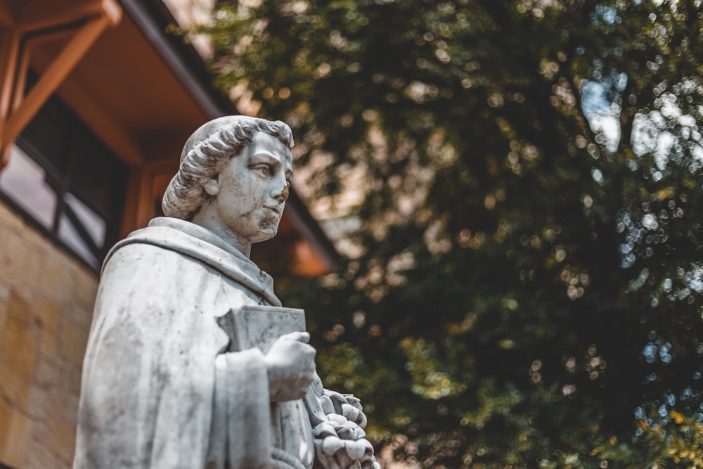 man holding book statue outdoor during daytime