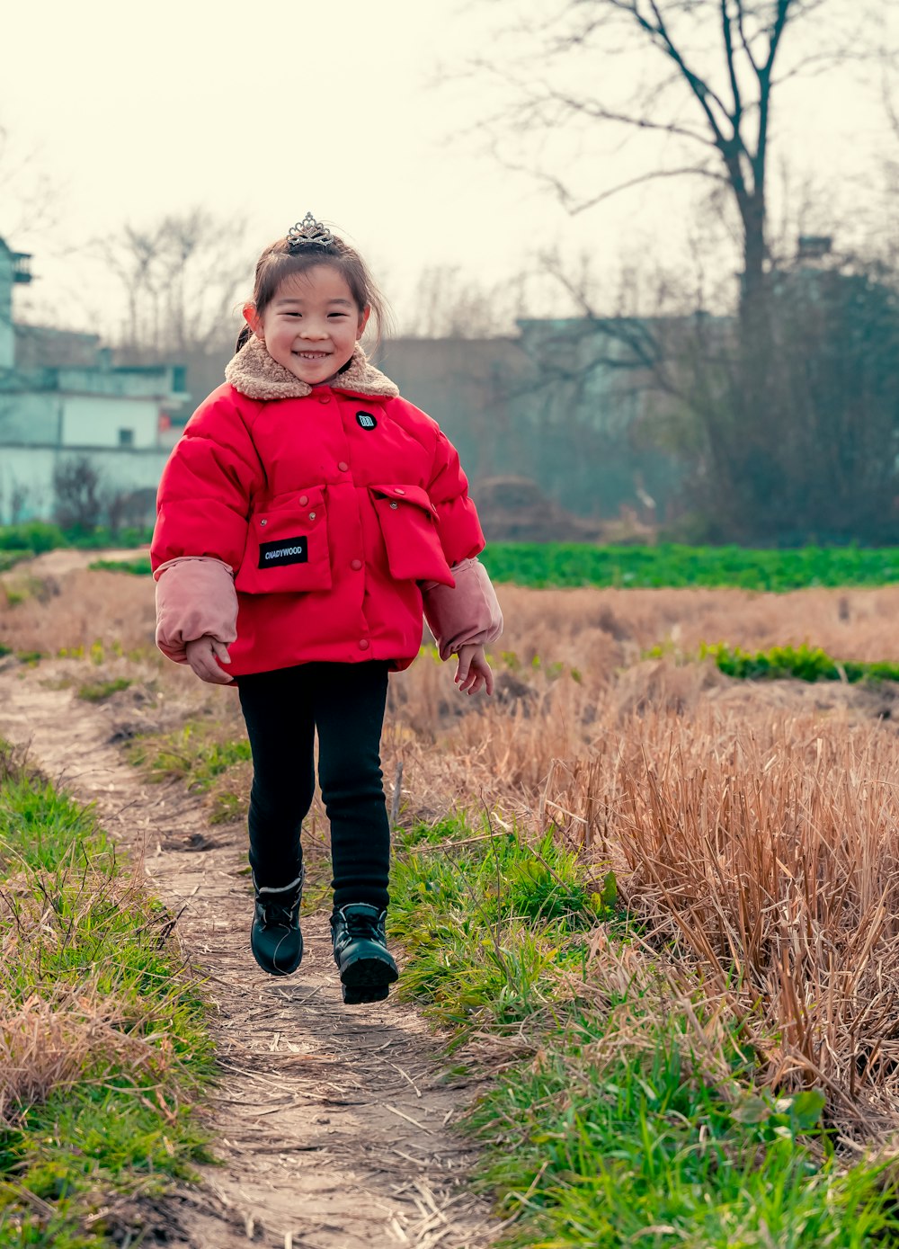 girl running on pathway near green grass during daytime