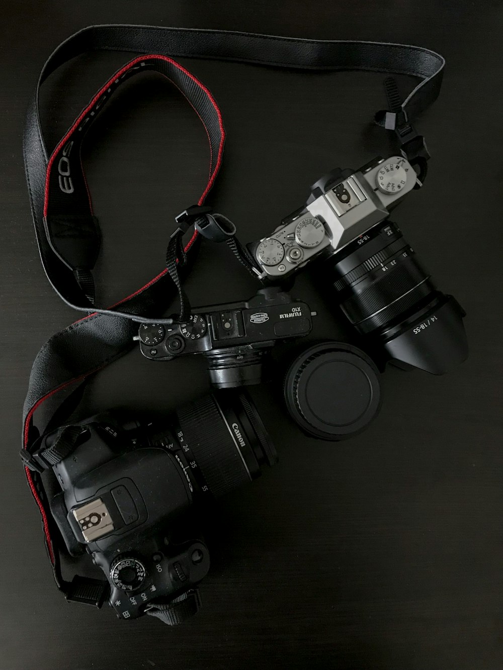 three black and gray DSLR cameras on table