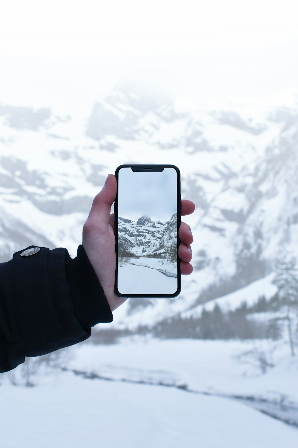 person taking picture at snow covered mountain