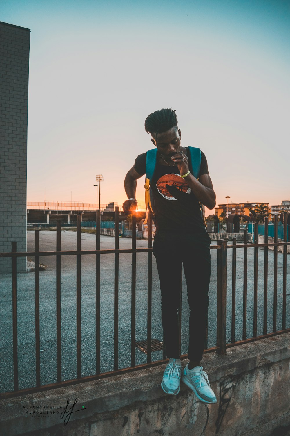 man holding fence near gray building during golden hour