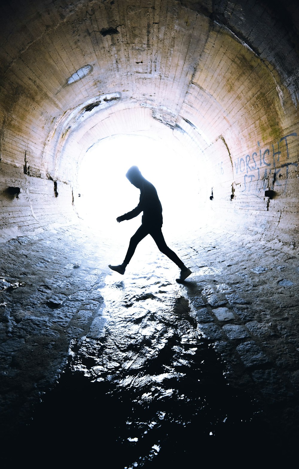 man walking inside tunnel during daytime