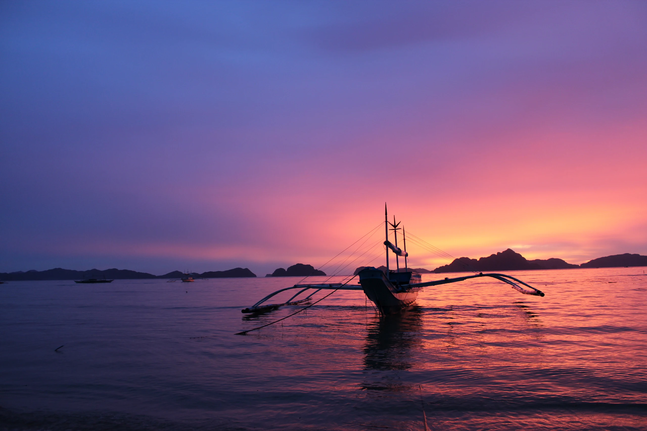 A couple's dinner table set on the sand at dusk on a private island in northern Palawan