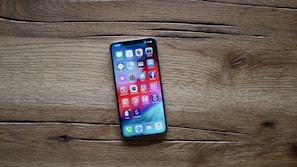Smartphone displayed on a wooden table with colorful app icons on screen