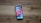 A smartphone with a colorful display full of app icons lies on a wooden surface. The screen shows various apps, including social media platforms, utilities, and games.