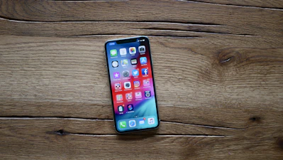 A sleek smartphone resting on a wooden table with vibrant app icons on the screen