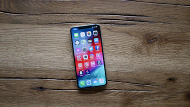 A vibrant smartphone display showcasing various apps and features on a wooden table.