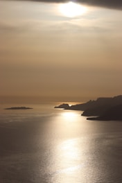 calm sea beside mountain during daytime