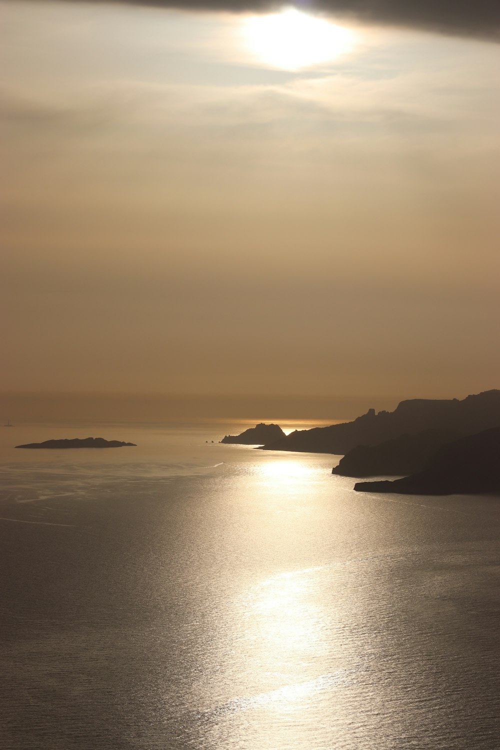 calm sea beside mountain during daytime