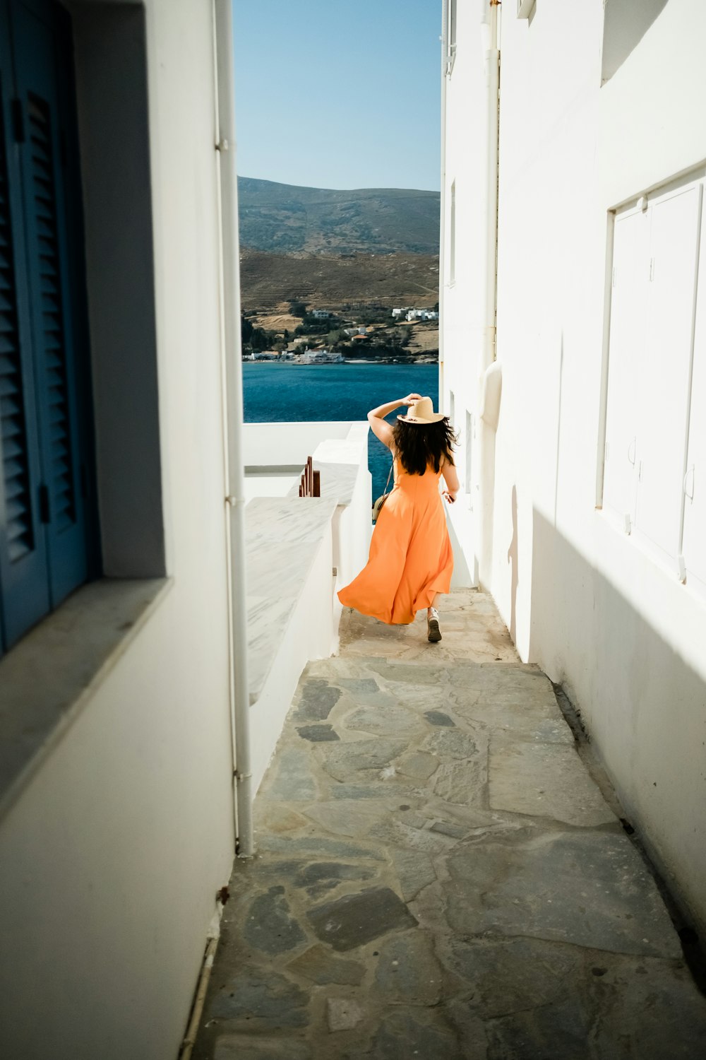 woman in orange sleeveless dress running through srairs