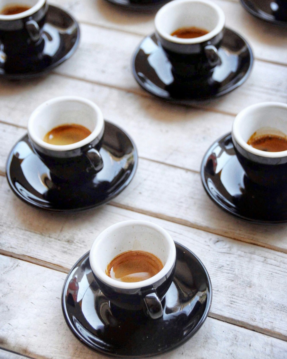 selective focus photography of four black-and-white ceramic cups and saucers
