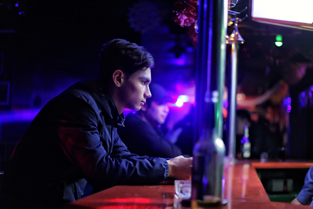 selective focus photography of man sitting in a bar