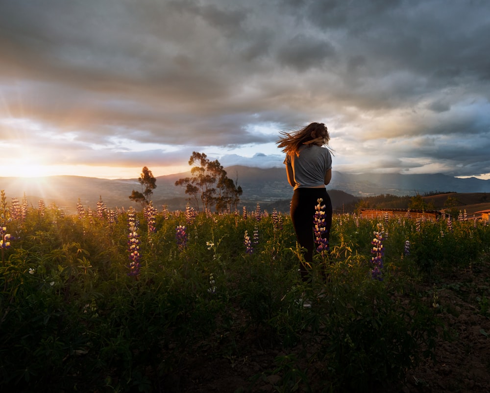 standing woman surrounded by flower during daytime