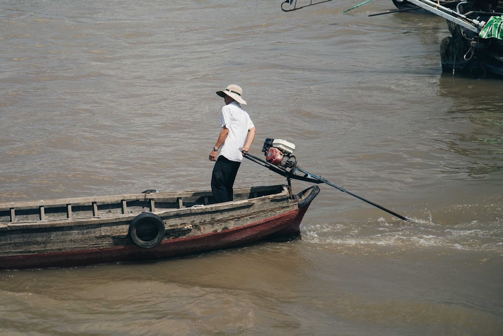 man in white t-shirt wearing hat riding speedboat