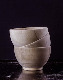 A set of small wooden bowls stacked neatly on a rustic wooden table.