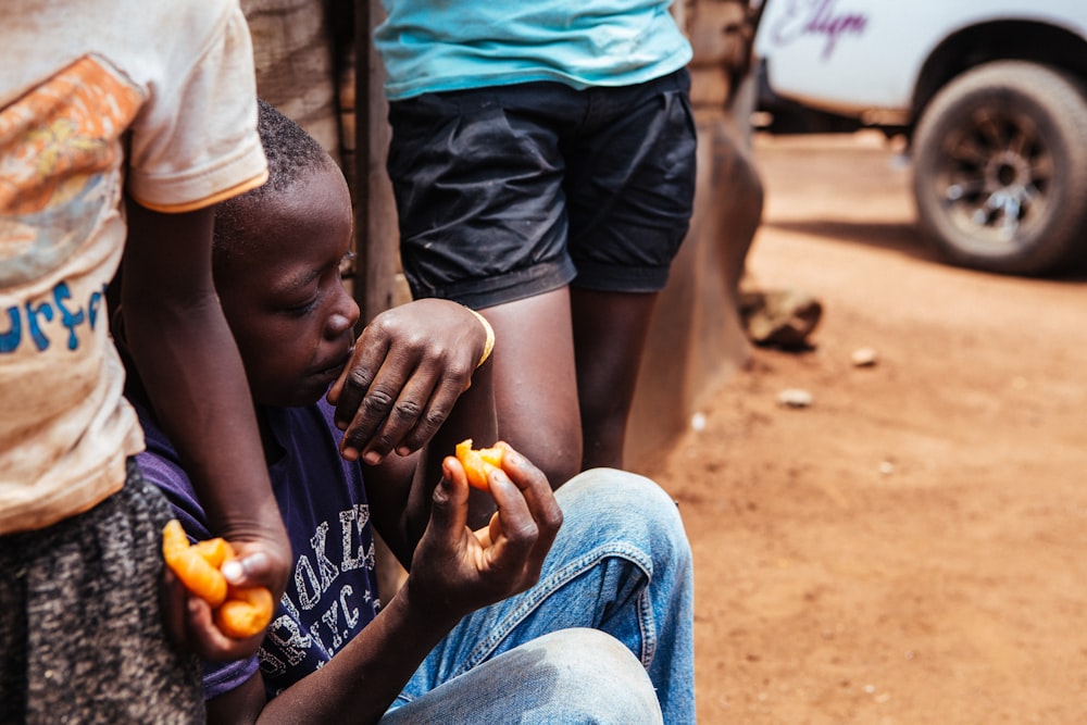 boy sitting while holding food during daytime