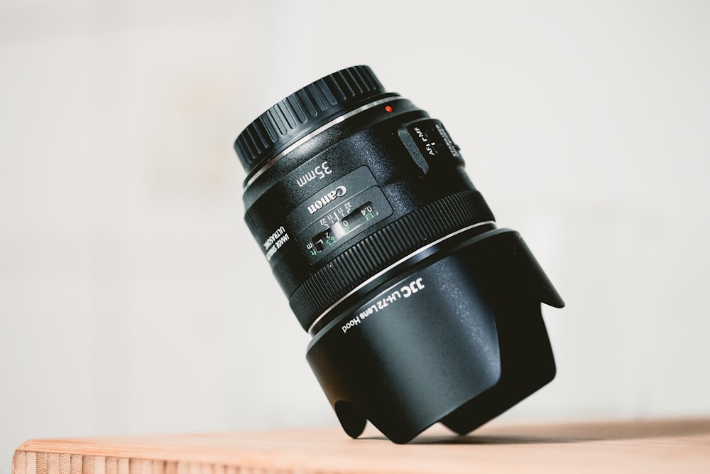 black Canon camera lens on brown wooden table