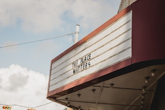 A vintage marquee sign with red trim displays the message 'THIS PLACE MATTERS' against a cloudy sky backdrop.