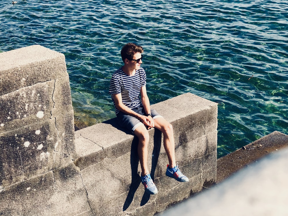 man sitting on gray pavement