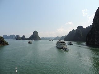A serene Ha Long Bay cruise boat gliding past towering limestone islands under a clear blue sky.