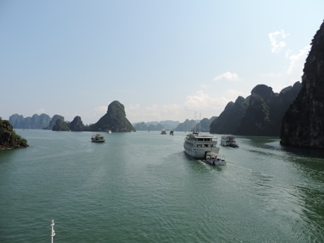 A serene Ha Long Bay cruise boat gliding past towering limestone islands under a clear blue sky.