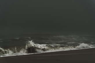 A dramatic storm rolling in over a wide-open Florida beach with crashing waves.