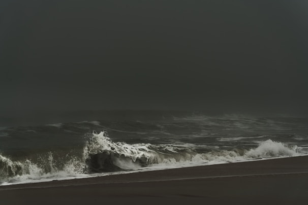 A dramatic storm rolling in over a wide-open Florida beach with crashing waves.
