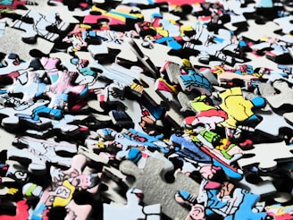 A colorful assortment of puzzle pieces scattered on a wooden table, hinting at a cartoon-themed puzzle in progress.
