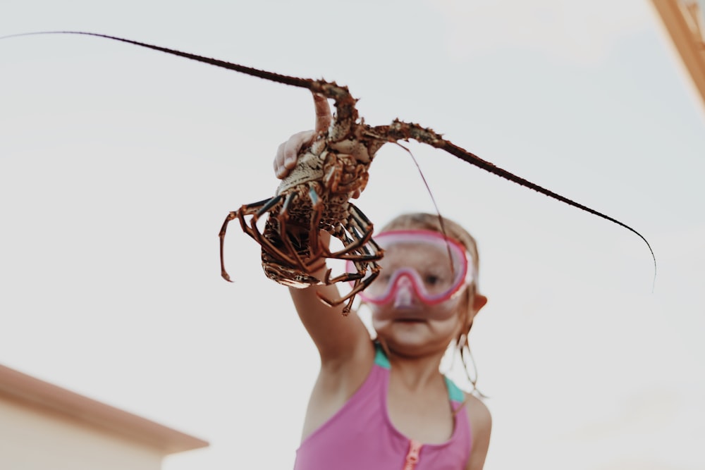 girl wearing goggles holding lobster