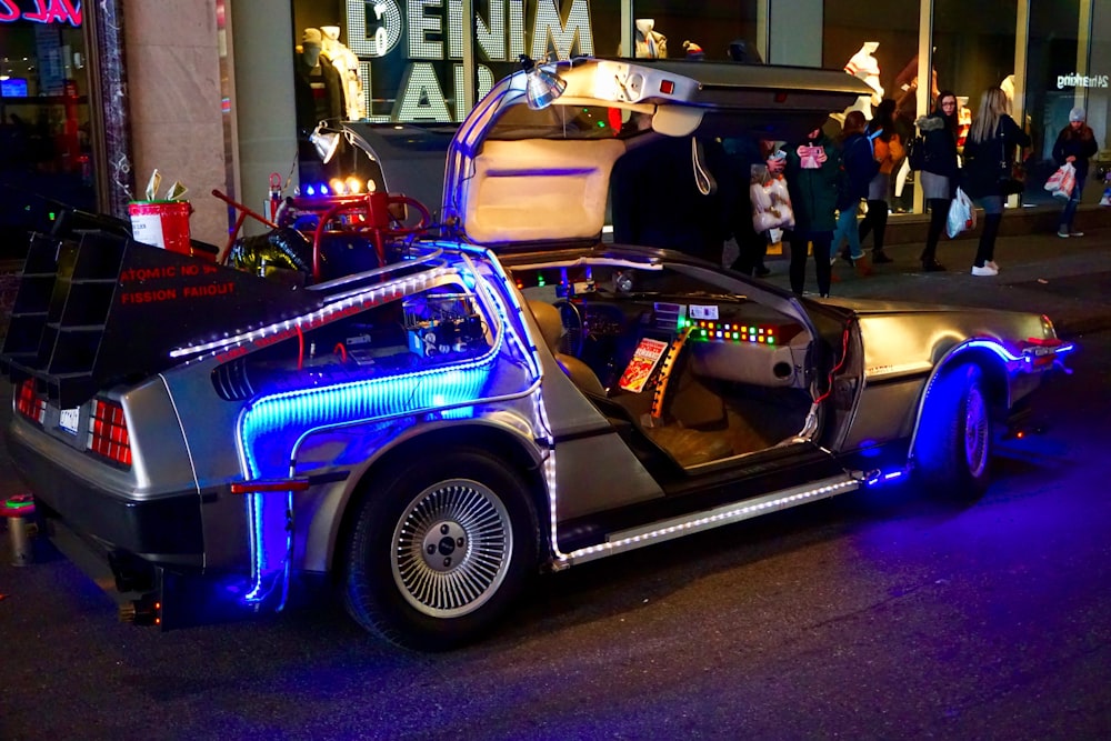 lighted silver gullwing coupe parked on sidewalk