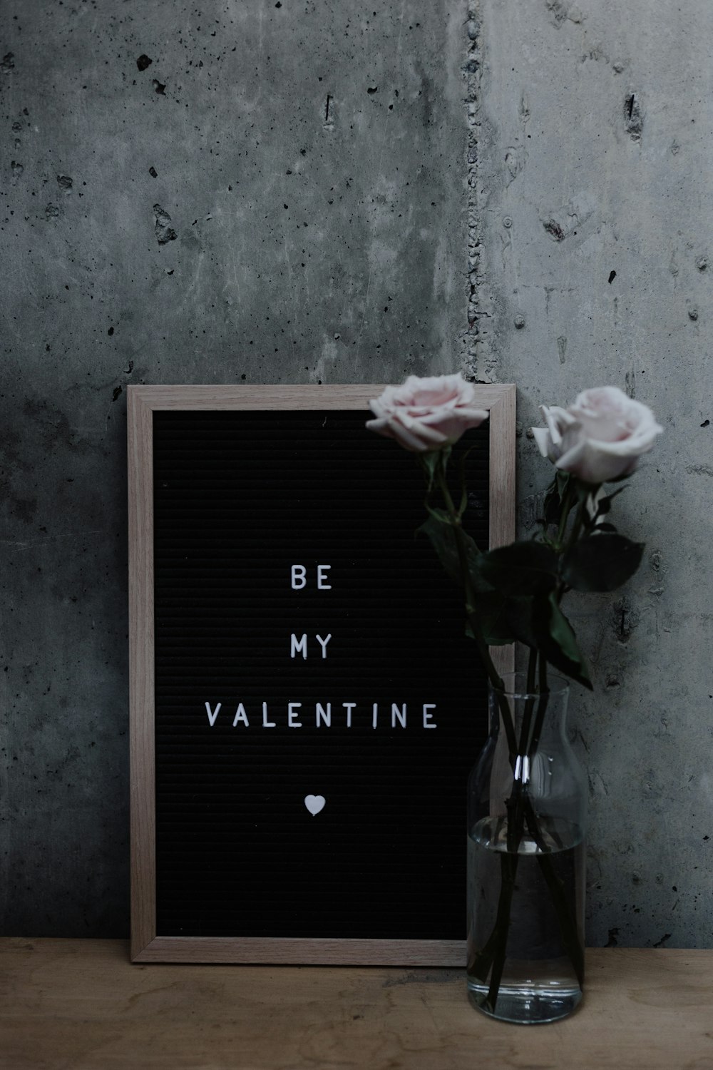 two white rose flowers in vase, with a sign that says Be My Valentine 